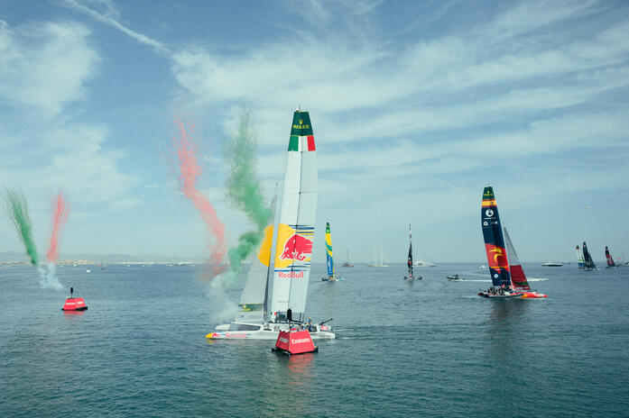 Racing and spectacle at the Spain Sail Grand Prix in Valencia. SailGP catamarans racing off Valencia’s waterfront, with coloured smoke rising beside the fleet.