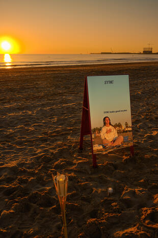 Brand presence at sunrise — Sync Club Sync Club event sign standing on a beach in warm sunrise light