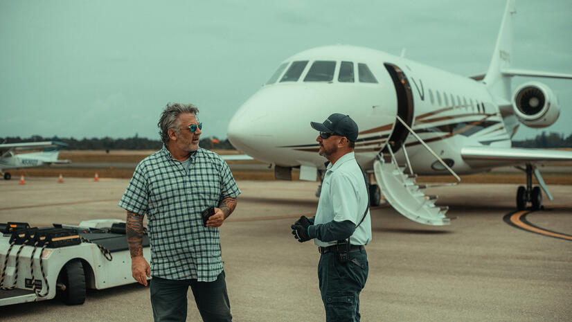 Aviation team on location Two aviation professionals talking on an airfield beside a private jet