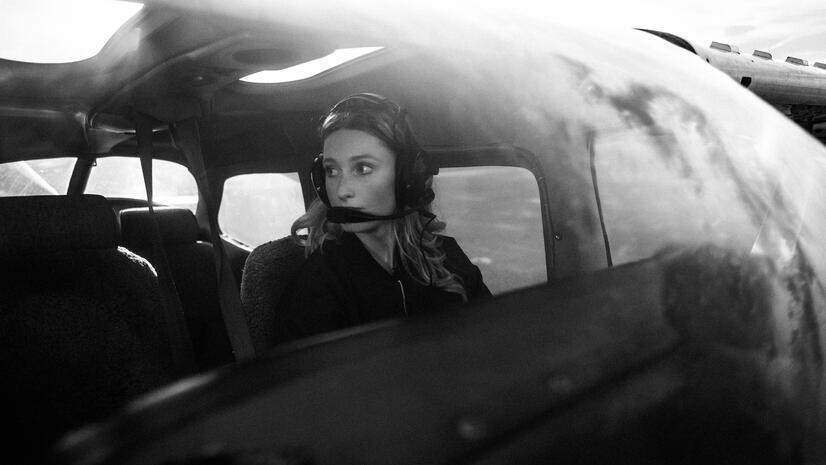 Aviation portrait in context Woman wearing an aviation headset inside a small aircraft, photographed through the cockpit window