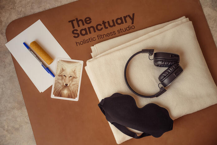 Experience details — The Sanctuary Branded Sanctuary fitness studio mat arranged with headphones, a blanket, an eye mask and printed materials
